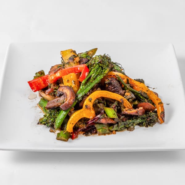 A vibrant soul-food stir-fry with broccoli, red and yellow bell peppers, and mushrooms on a white plate.